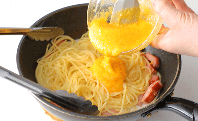 パスタに卵を加えている写真